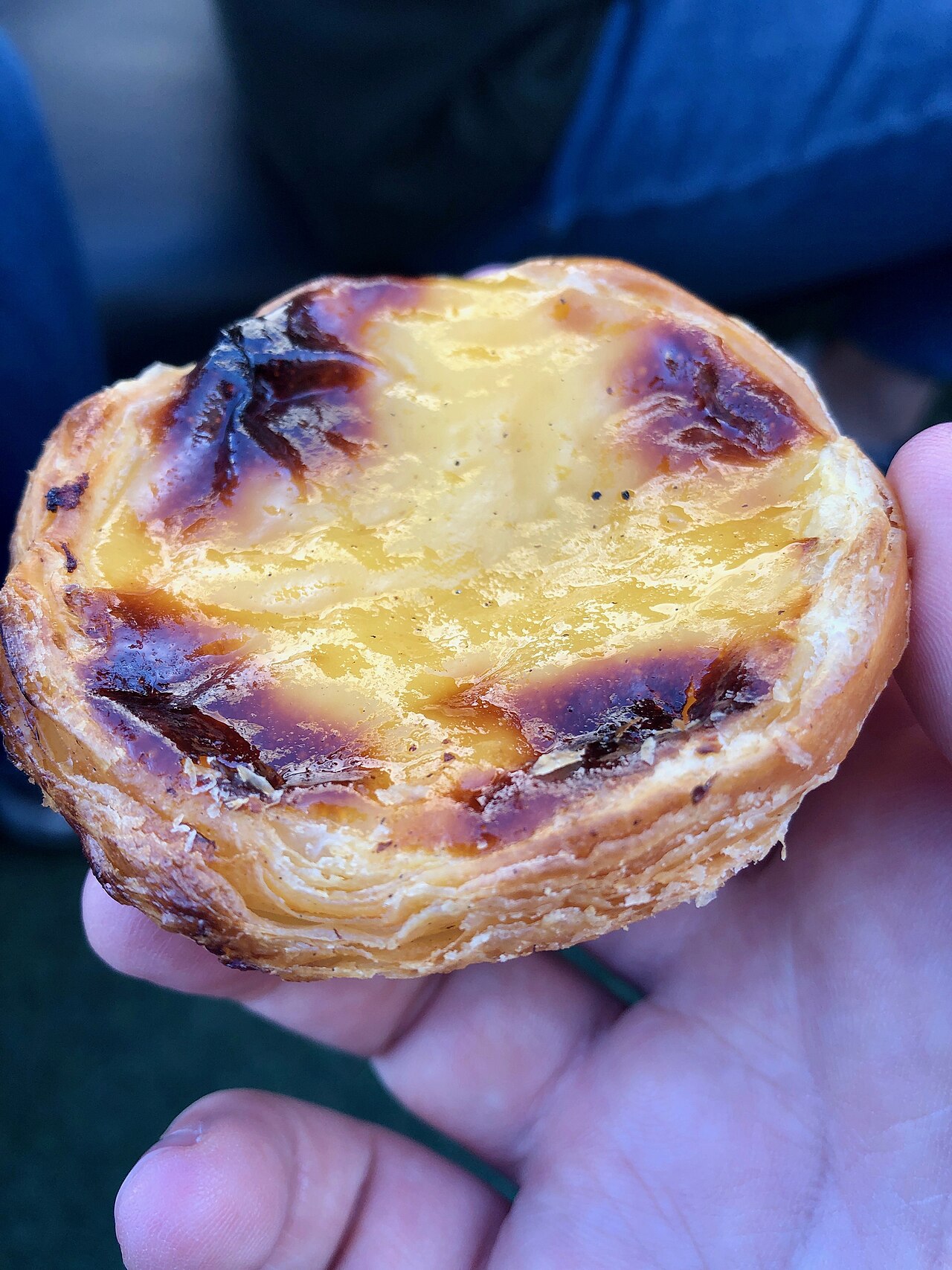 A freshly baked pastel de nata held in one hand in Lisbon