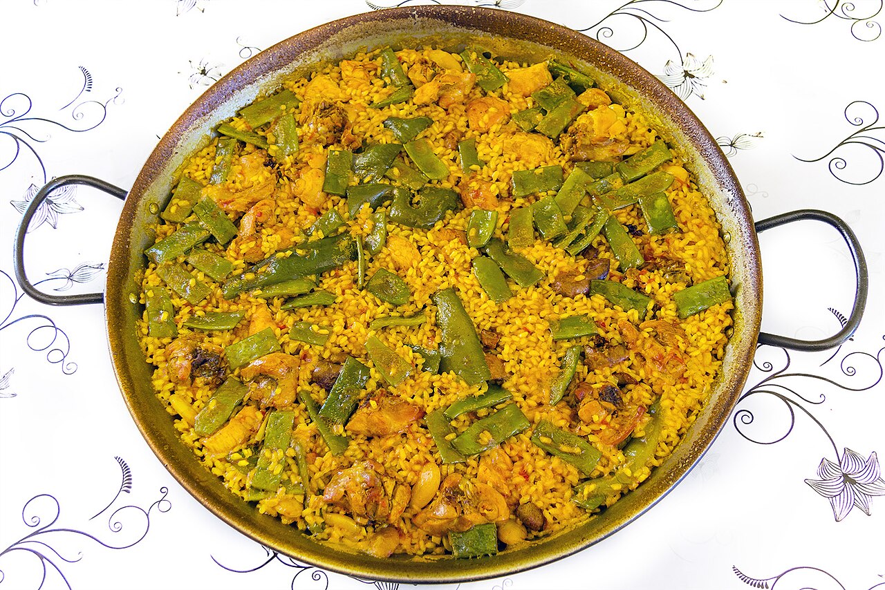 A wide pan of paella Valenciana with rice, beans and meat