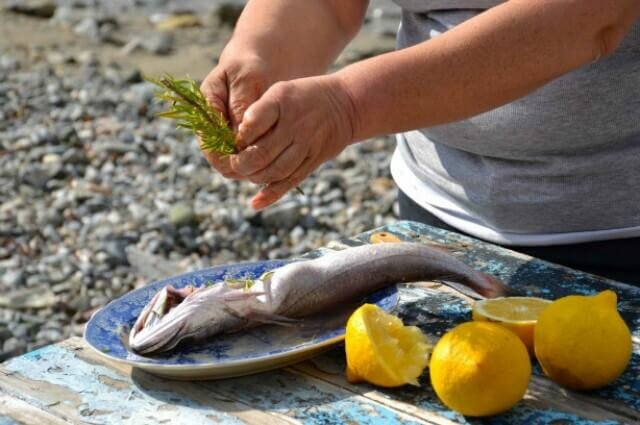 Cooking fish and seasoning it on holiday in Greece